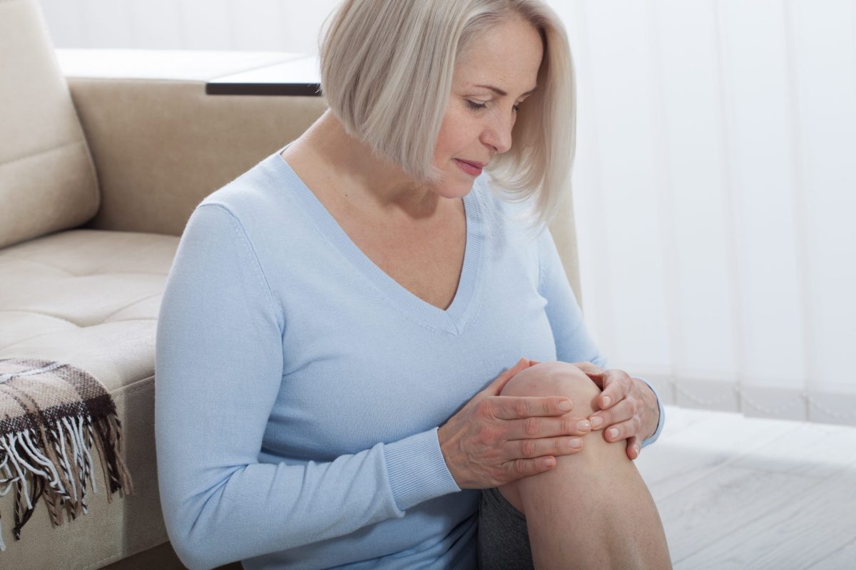 Middle-aged woman suffering from pain in leg at home, closeup. Physical injury concept. Ankle pain, painful point.